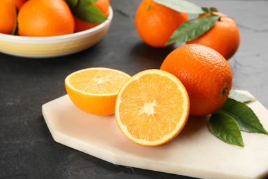 Photo of Whole and cut delicious ripe oranges on black table