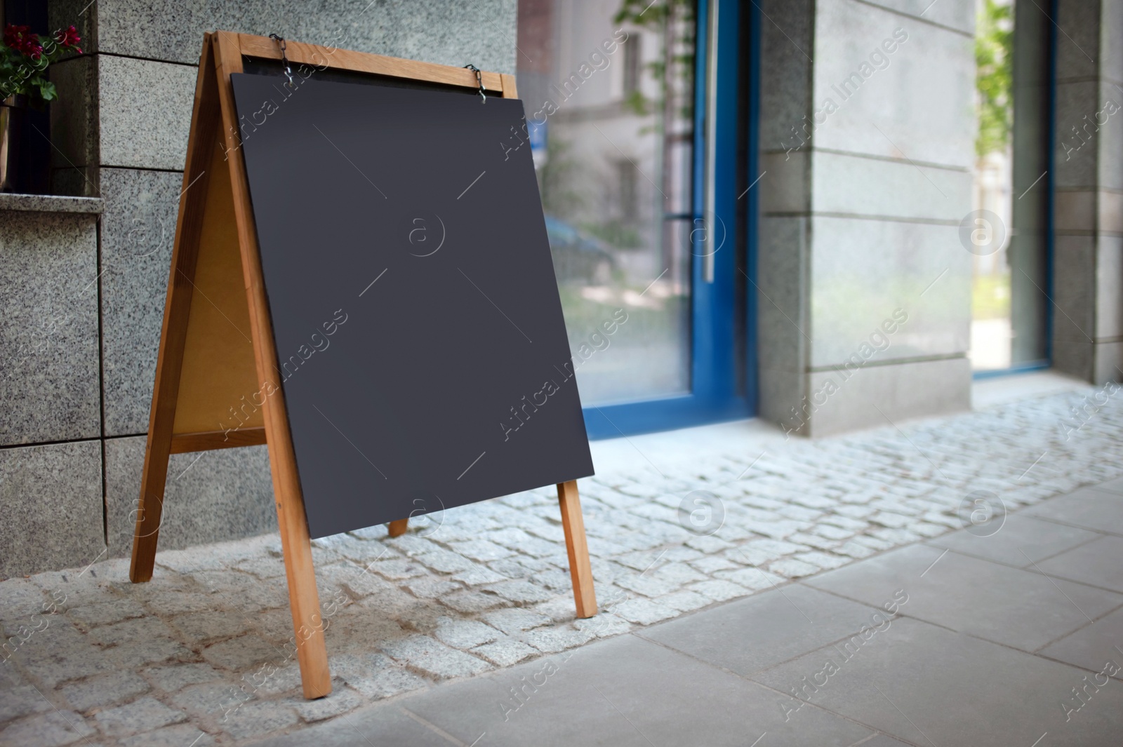 Photo of Blank advertising A-board near cafe. Mockup for design