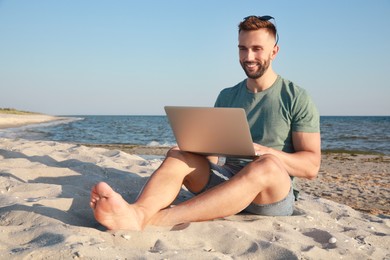 Man working with modern laptop on beach