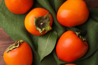 Delicious ripe persimmons on wooden table, flat lay