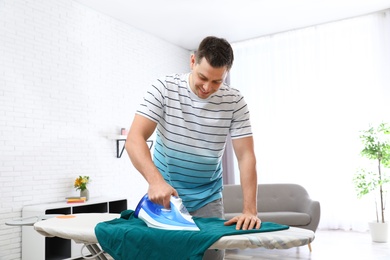 Man ironing clothes on board at home