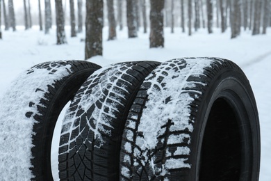 New winter tires covered with snow near forest, closeup