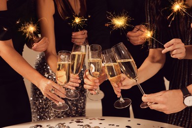 Photo of Friends clinking glasses of sparkling wine, closeup. New Year celebration