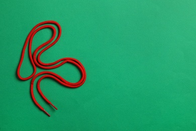 Photo of Red shoelace on green background, top view. Space for text