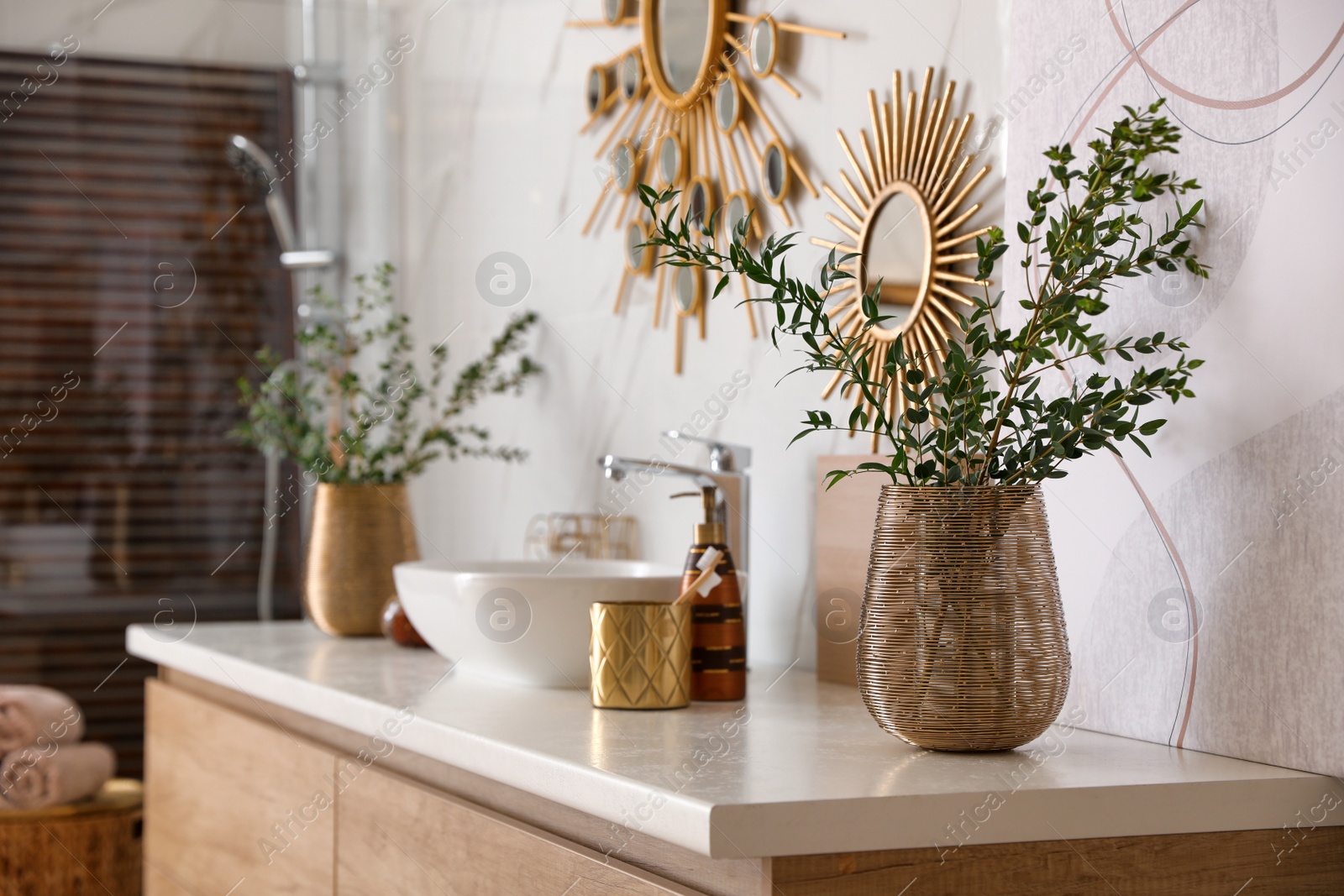 Photo of Vase with beautiful branches and toiletries near vessel sink in bathroom. Interior design