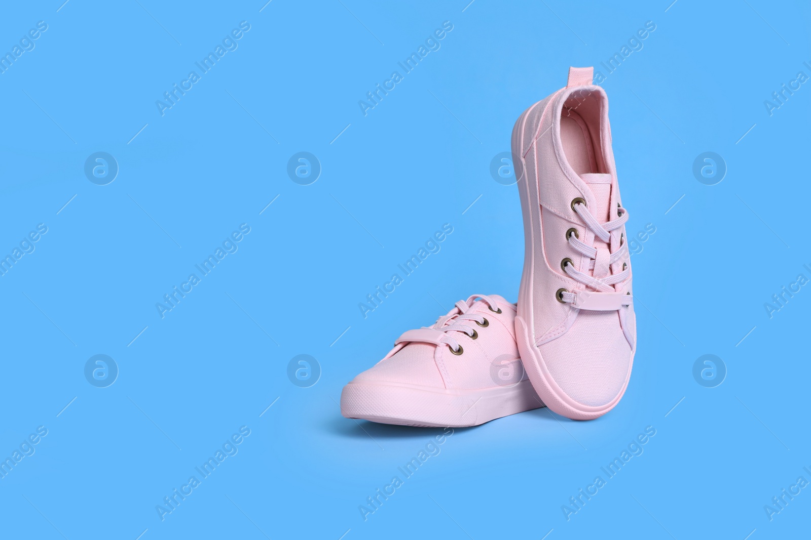 Photo of Pair of comfortable sports shoes on turquoise background. Space for text