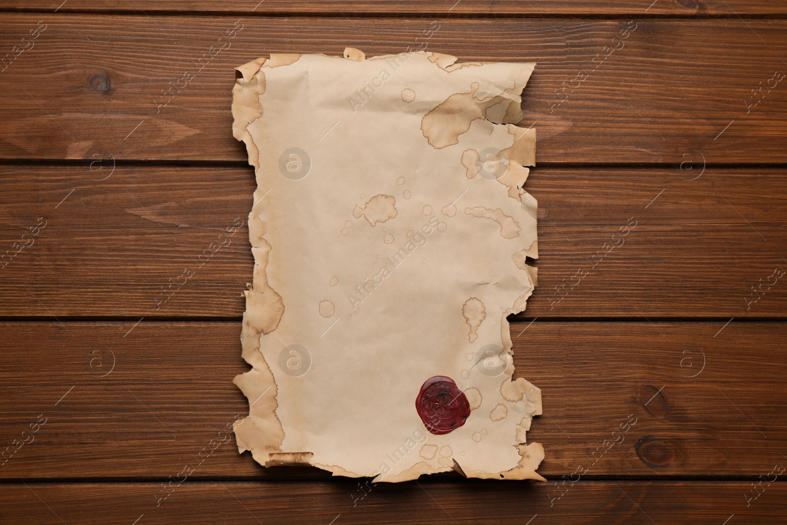 Photo of Sheet of old parchment paper with wax stamp on wooden table, top view. Space for design