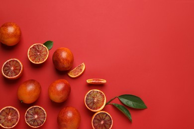 Photo of Many ripe sicilian oranges and leaves on red background, flat lay. Space for text