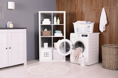 Photo of Washing machine with towels in laundry room interior