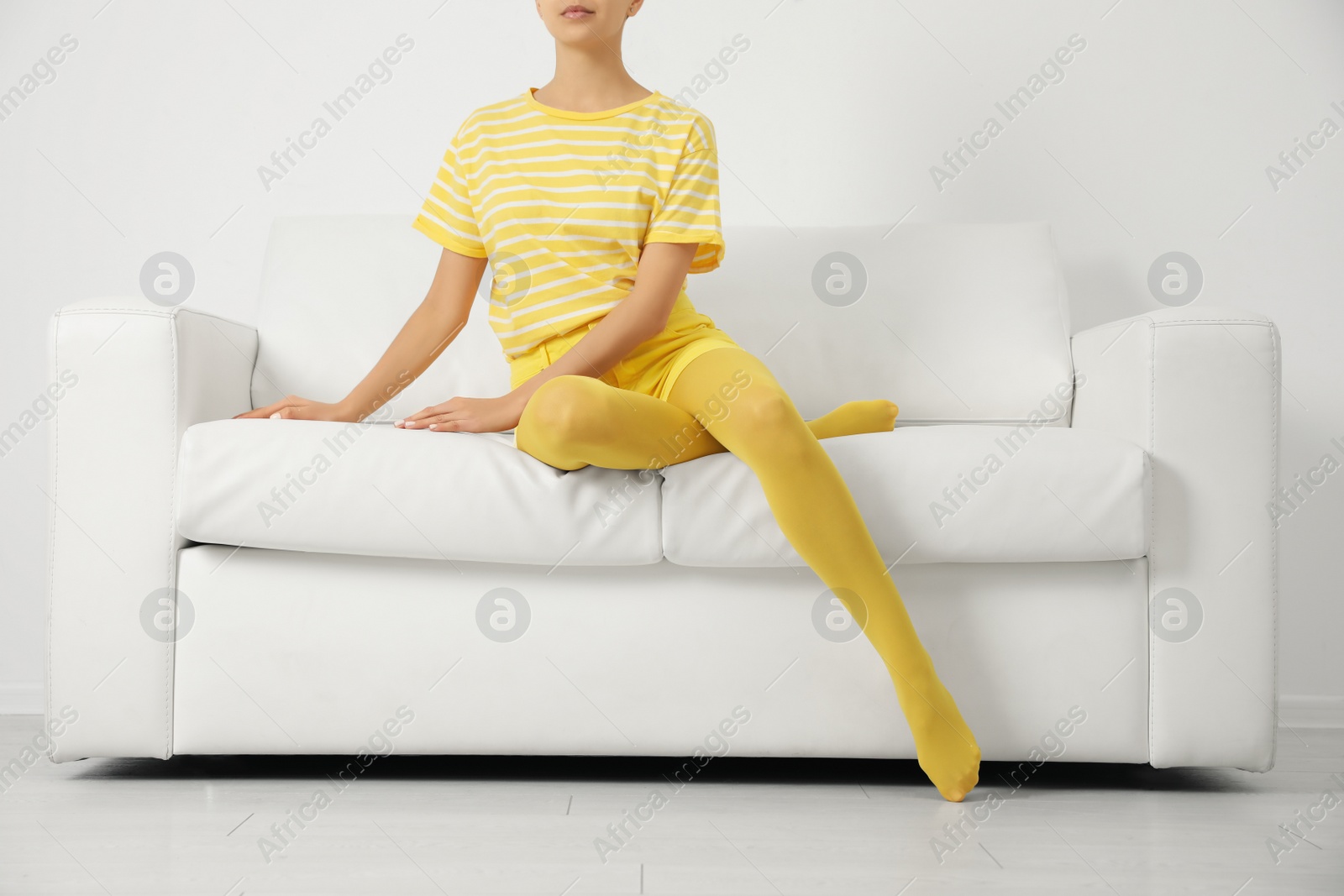 Photo of Woman wearing yellow tights sitting on sofa indoors, closeup