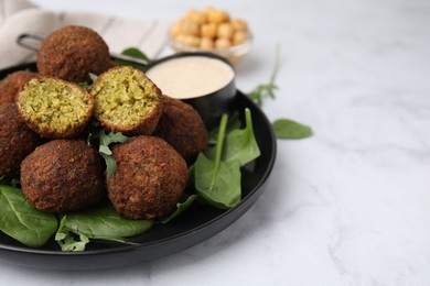 Delicious falafel balls, herbs and sauce on white marble table, closeup. Space for text