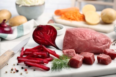 Photo of Fresh ingredients for borscht on white board, closeup