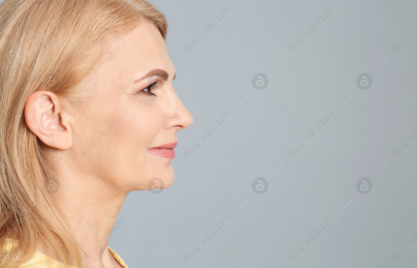 Photo of Portrait of mature woman with beautiful face on grey background. Space for text