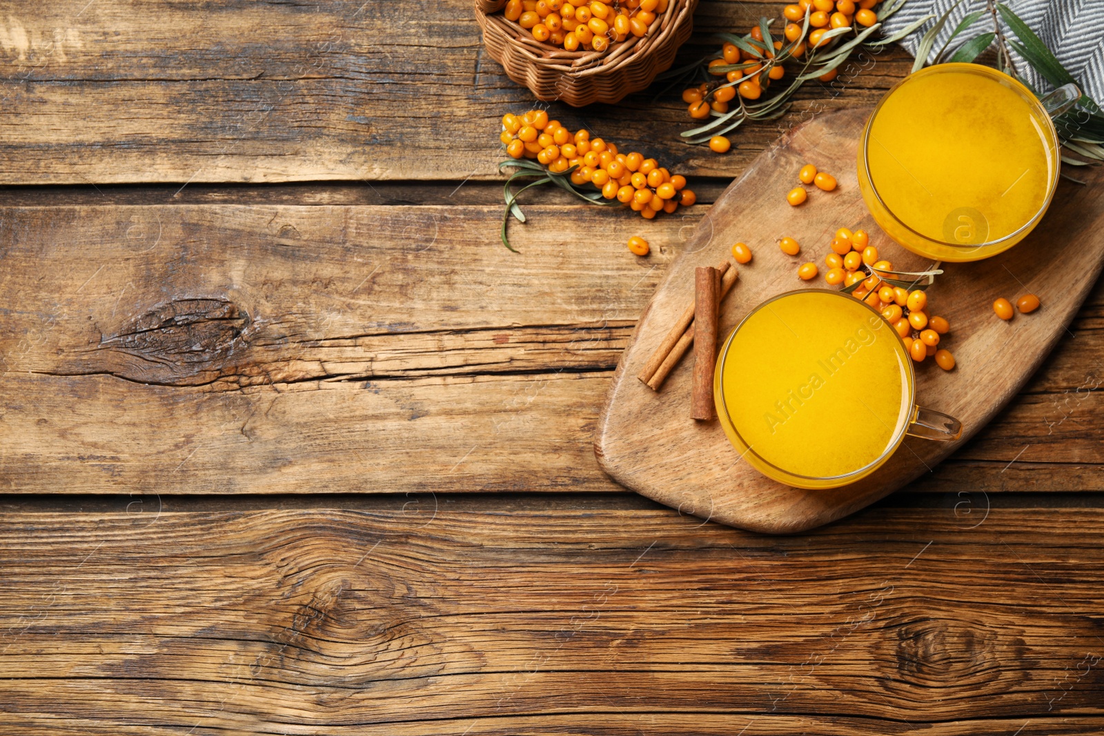 Photo of Sea buckthorn tea and fresh berries on wooden table, flat lay. Space for text