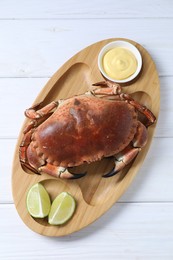 Delicious boiled crab served with lime and sauce on white wooden table, top view