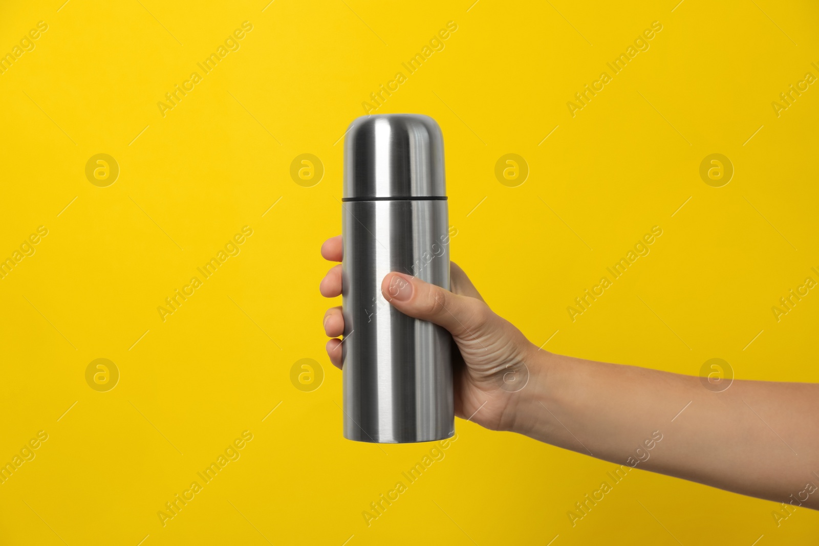 Photo of Woman holding modern thermos on yellow background, closeup