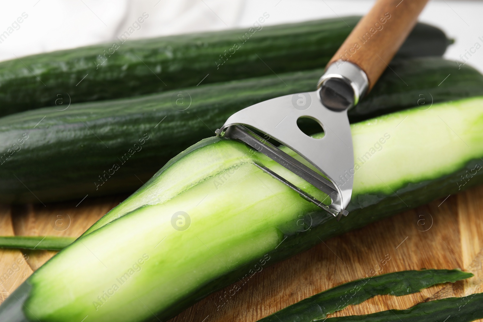 Photo of Fresh cucumbers and peeler on table, closeup