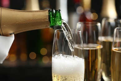 Photo of Pouring champagne into glass on blurred background, closeup