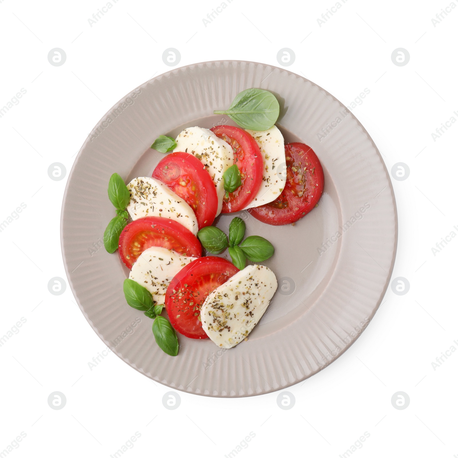 Photo of Plate of delicious Caprese salad with tomatoes, mozzarella, basil and spices isolated on white, top view