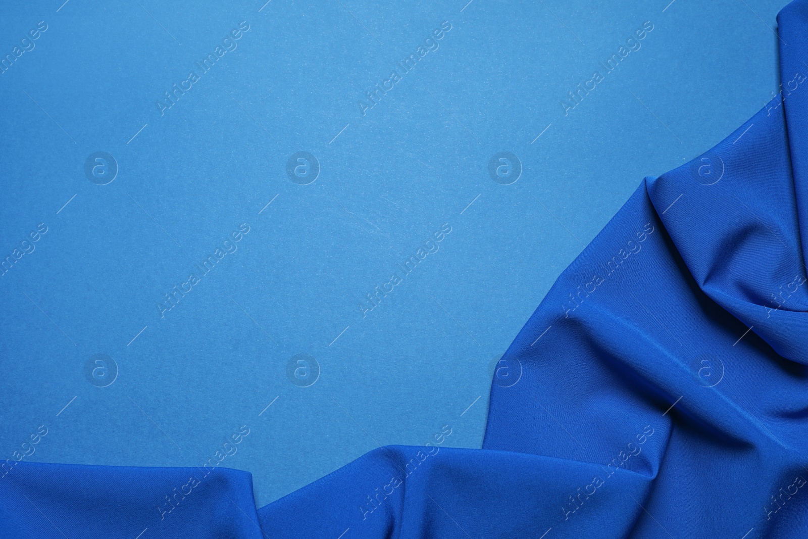 Photo of Crumpled fabric and space for text on bright background, top view. Color of the year 2020 (Classic blue)
