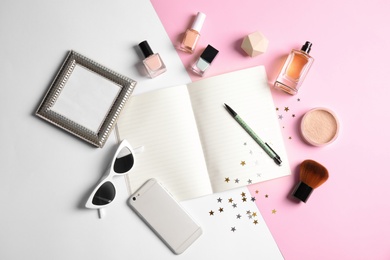 Photo of Flat lay composition with blank notebook, cosmetics and phone on color background, space for text. Blogger's workplace