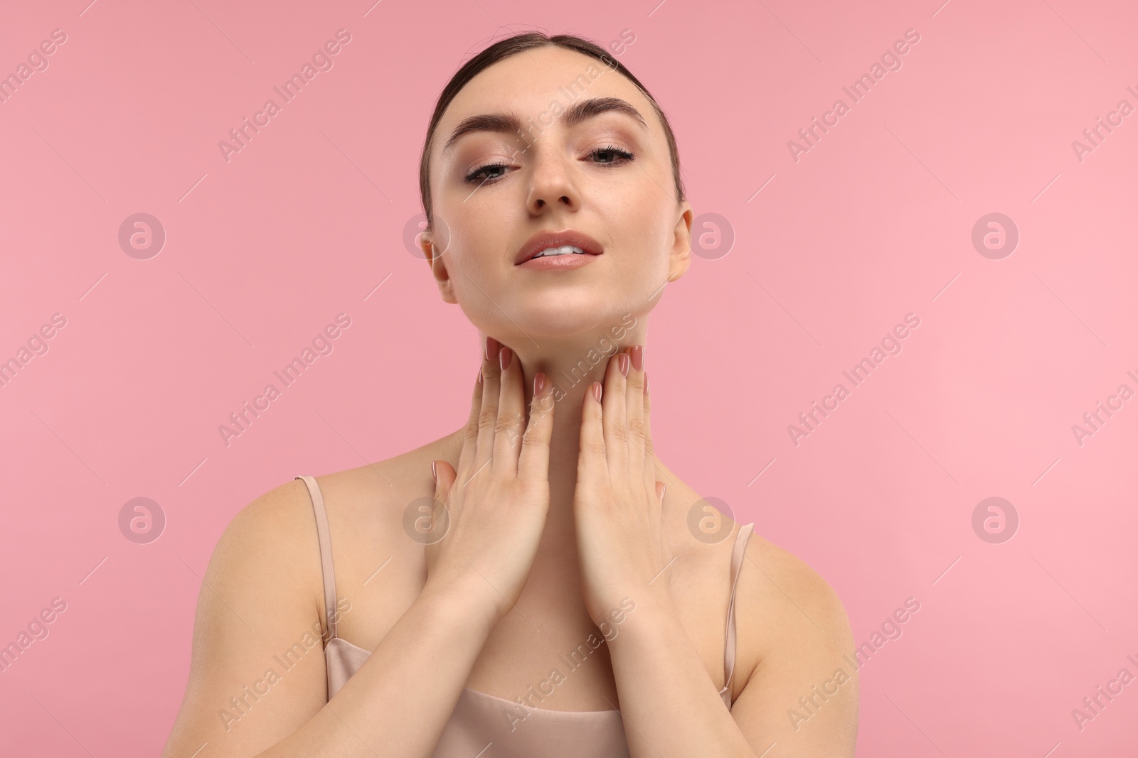 Photo of Beautiful woman touching her neck on pink background