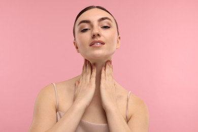 Photo of Beautiful woman touching her neck on pink background