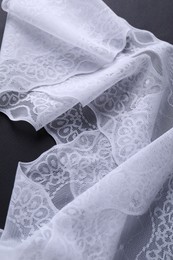 Photo of White lace on black background, top view