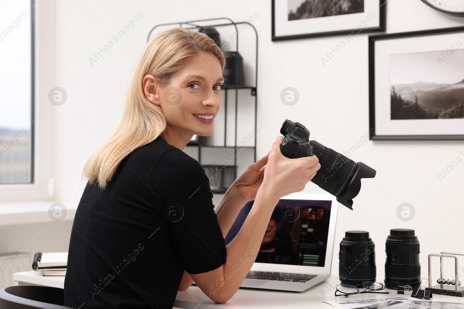 Photo of Professional photographer with digital camera at table in office