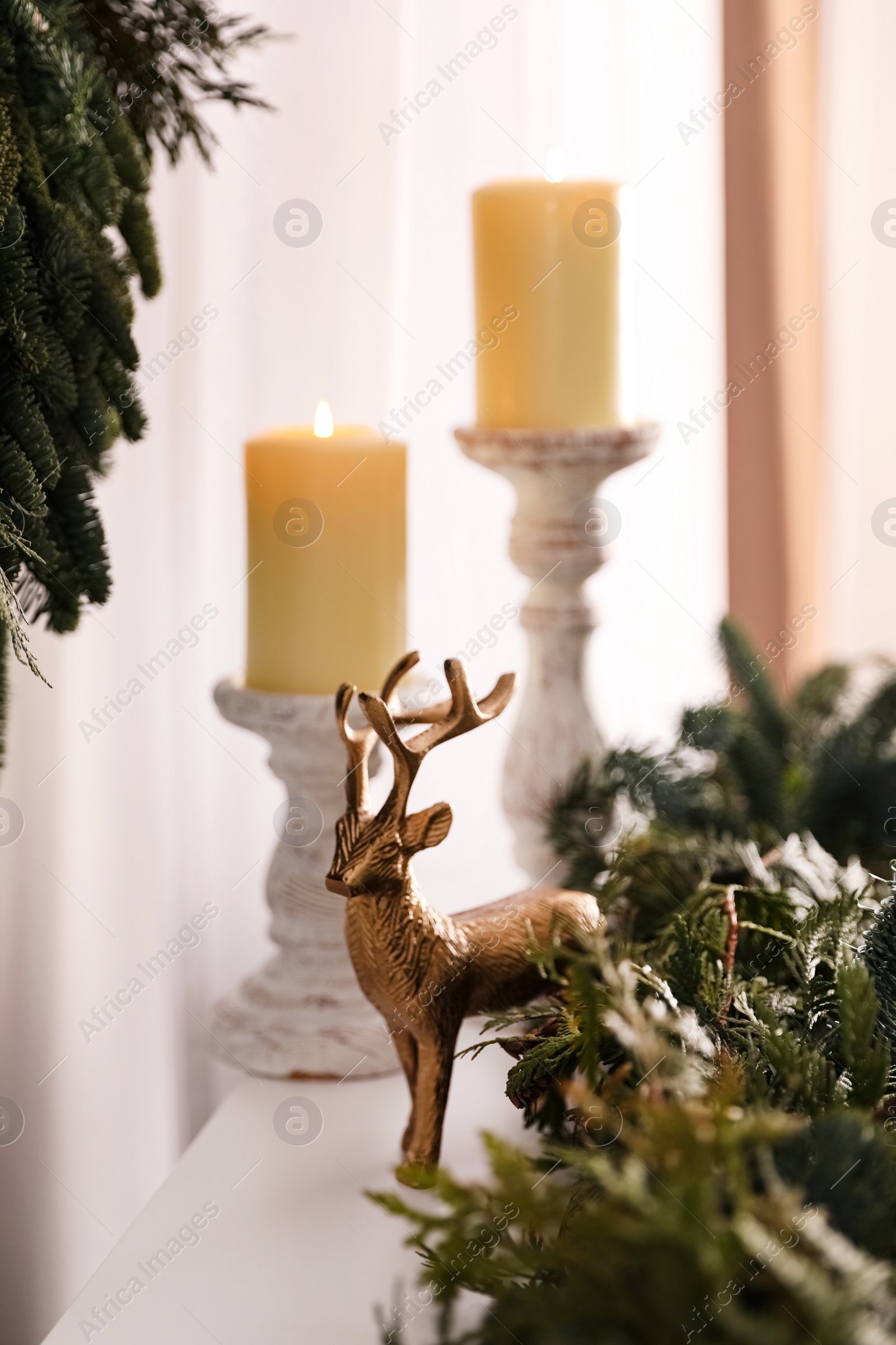 Photo of Christmas composition with decorative reindeer and candles near fir tree branches