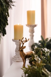 Photo of Christmas composition with decorative reindeer and candles near fir tree branches