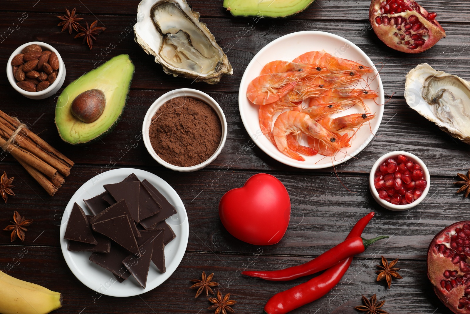 Photo of Natural aphrodisiac. Different food products and red decorative heart on dark wooden table, flat lay