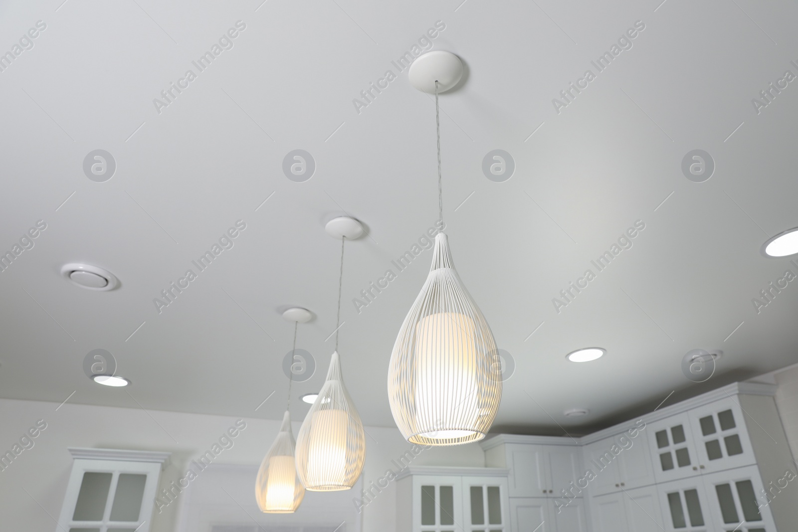 Photo of Modern pendant lamps on white ceiling indoors