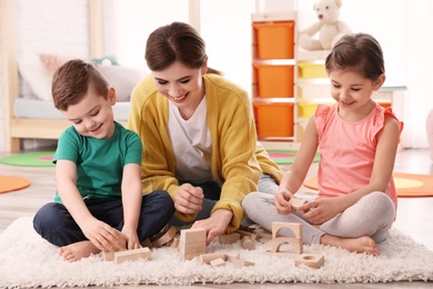 Nanny and little children playing at home