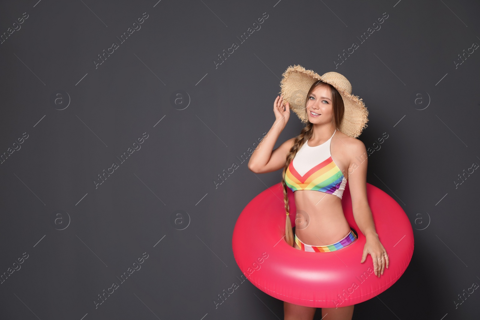 Photo of Beautiful young woman in bikini with inflatable ring against dark background. Space for text