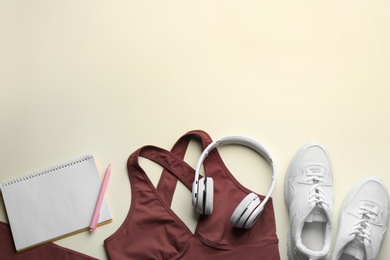 Flat lay composition with sportswear and notebook on light background, space for text. Gym workout plan