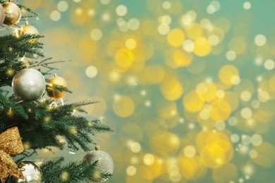 Image of Beautiful Christmas tree with bright baubles against blurred lights on turquoise background, closeup. Space for text