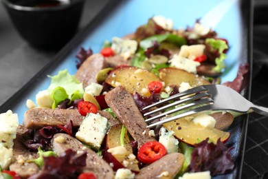 Delicious salad with beef tongue, cheese and fork served on table, closeup