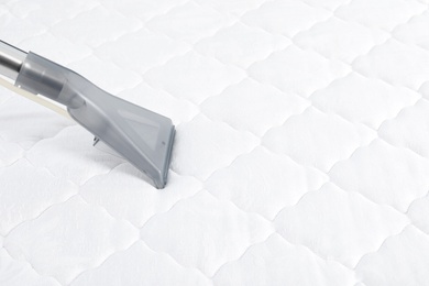 Using modern vacuum cleaner for mattress disinfection, closeup. Space for text