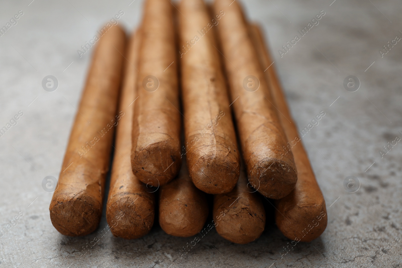 Photo of Many expensive cigars on grey table, closeup