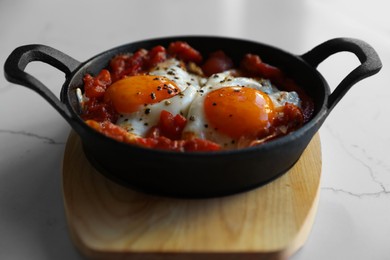 Tasty Shakshouka served in pan on white table, closeup