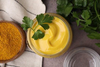 Tasty curry sauce, powder and parsley on brown table, flat lay