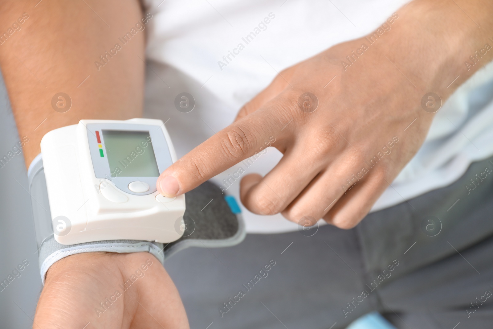Photo of Young man checking pulse with blood pressure monitor on wrist, closeup