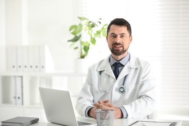 Portrait of male doctor in white coat at workplace