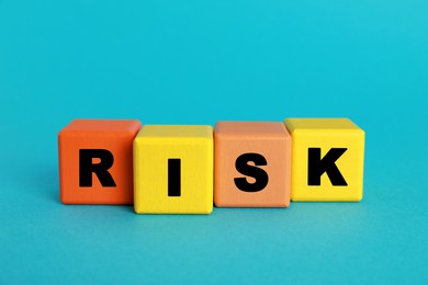 Photo of Word Risk made of colorful cubes on turquoise background