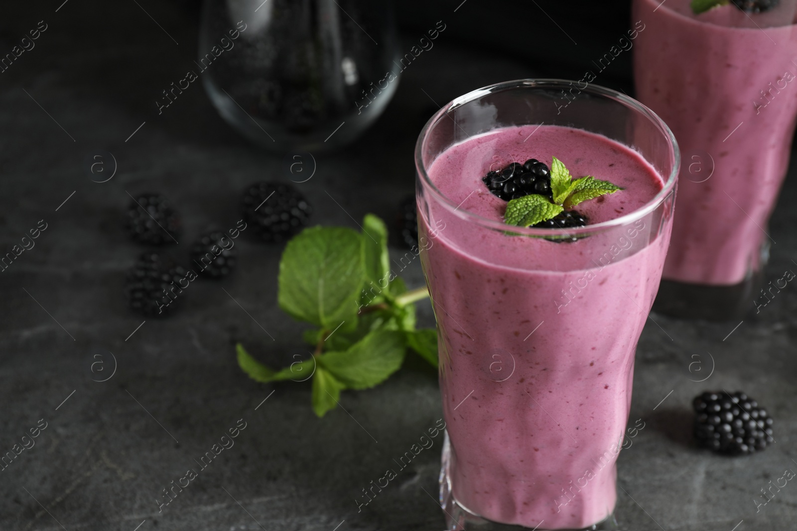 Photo of Glass of tasty blackberry smoothie on grey table. Space for text