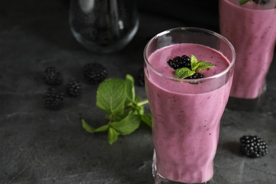 Photo of Glass of tasty blackberry smoothie on grey table. Space for text