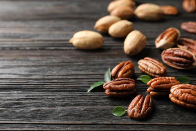 Photo of Tasty pecan nuts scattered on wooden table. Space for text