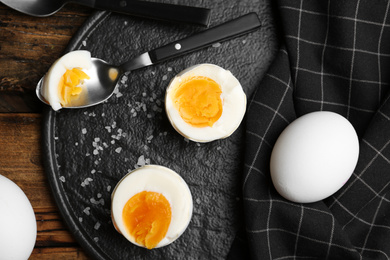 Photo of Tasty boiled chicken eggs on black slate plate, flat lay