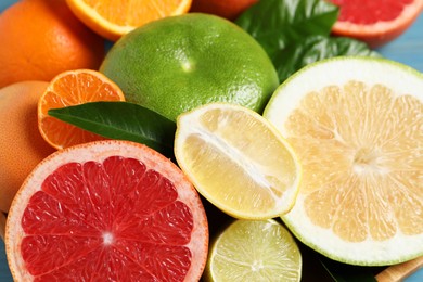 Photo of Different citrus fruits with fresh leaves, closeup